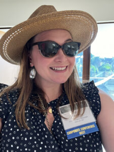 Diana Harmon, Board Secretary, pictured in a polka dot top, a hat, and sunglasses.