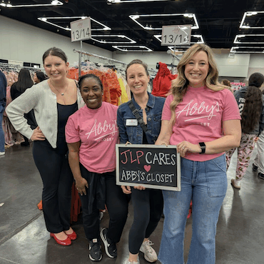 4 volunteers holding a sign with "JLP CARES Abby's Closet" written on it