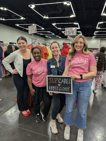4 volunteers holding a sign with "JLP CARES Abby's Closet" written on it